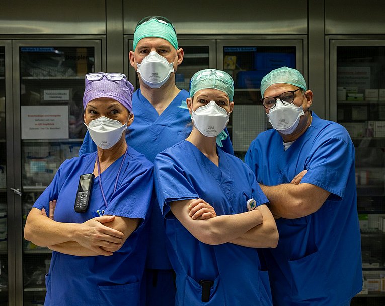 Das Bild zeigt vier Menschen, zwei Männer (einen Arzt und einen Pfleger) und zwei Frauen (eine Ärztin und eine Pflegerin).